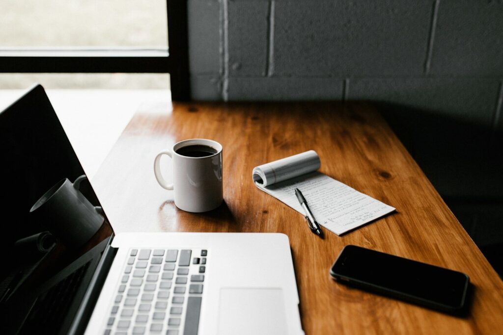 Portátil, taza y móvil sobre una mesa de trabajo
